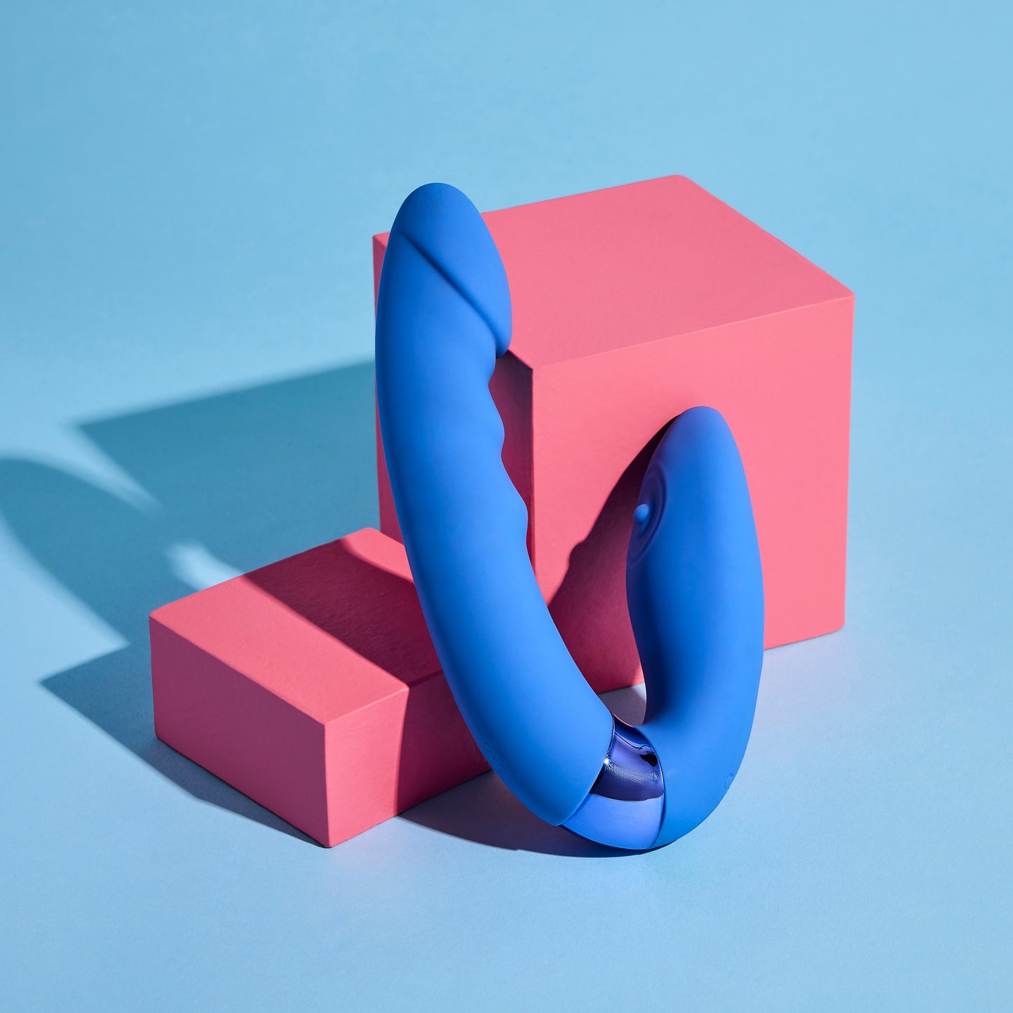 Blue vibrator on pink geometric blocks against a blue background