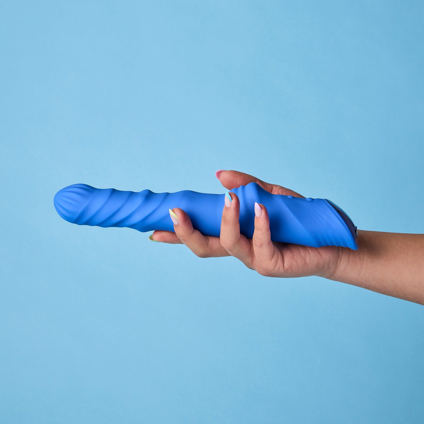 Hand holding a blue silicone vibrator against a light blue background