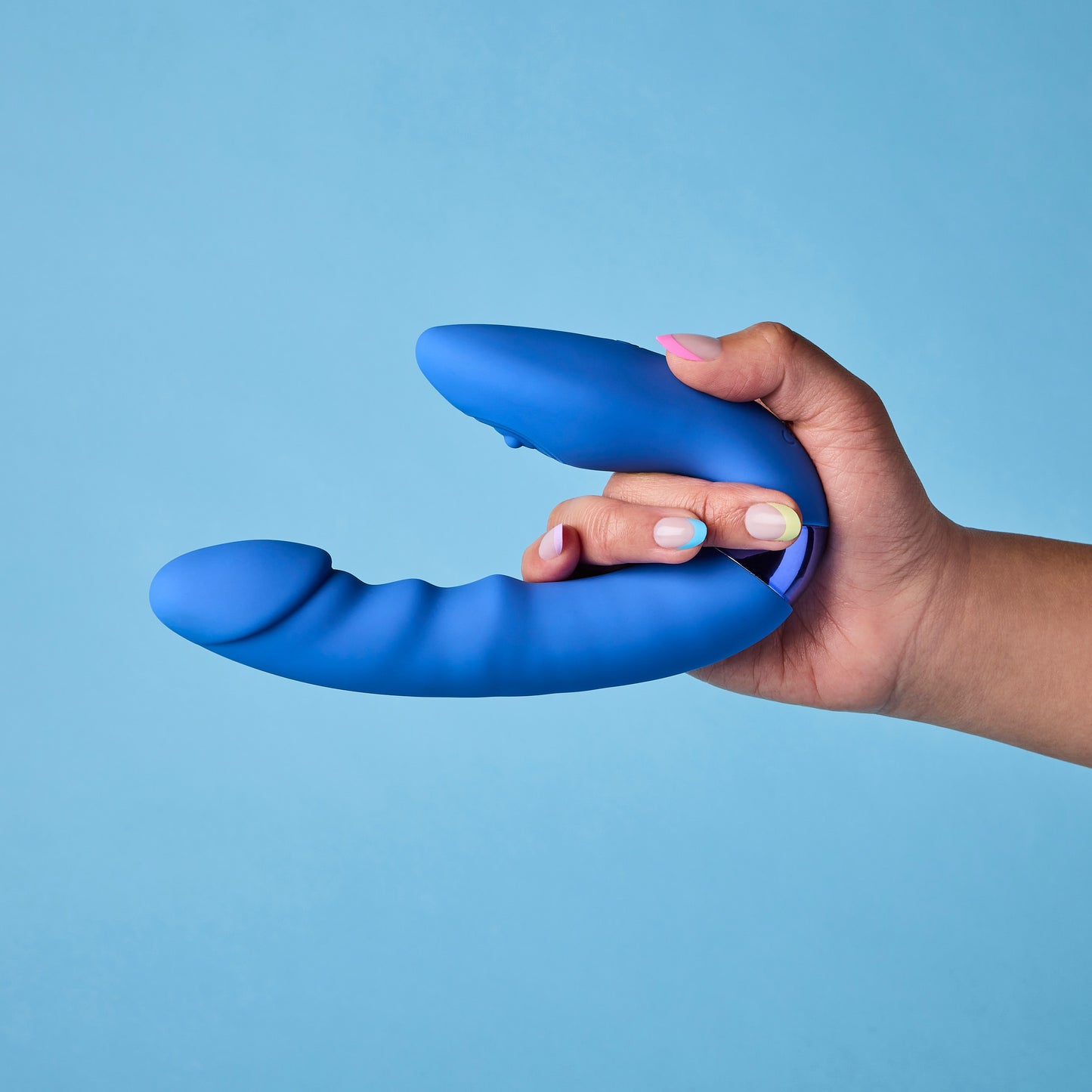 Hand holding a blue silicone vibrator against a light blue background