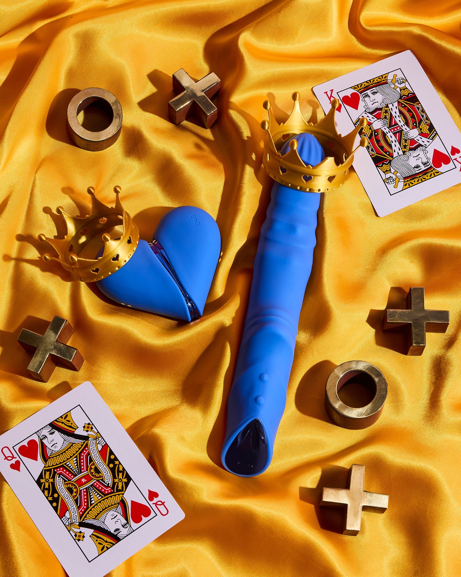 Blue toy with gold crown on a yellow fabric background with playing cards and gold symbols.