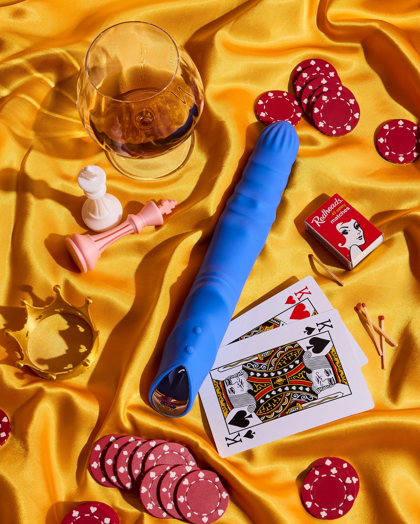 Blue silicone vibrator on a yellow fabric background with playing cards and poker chips.