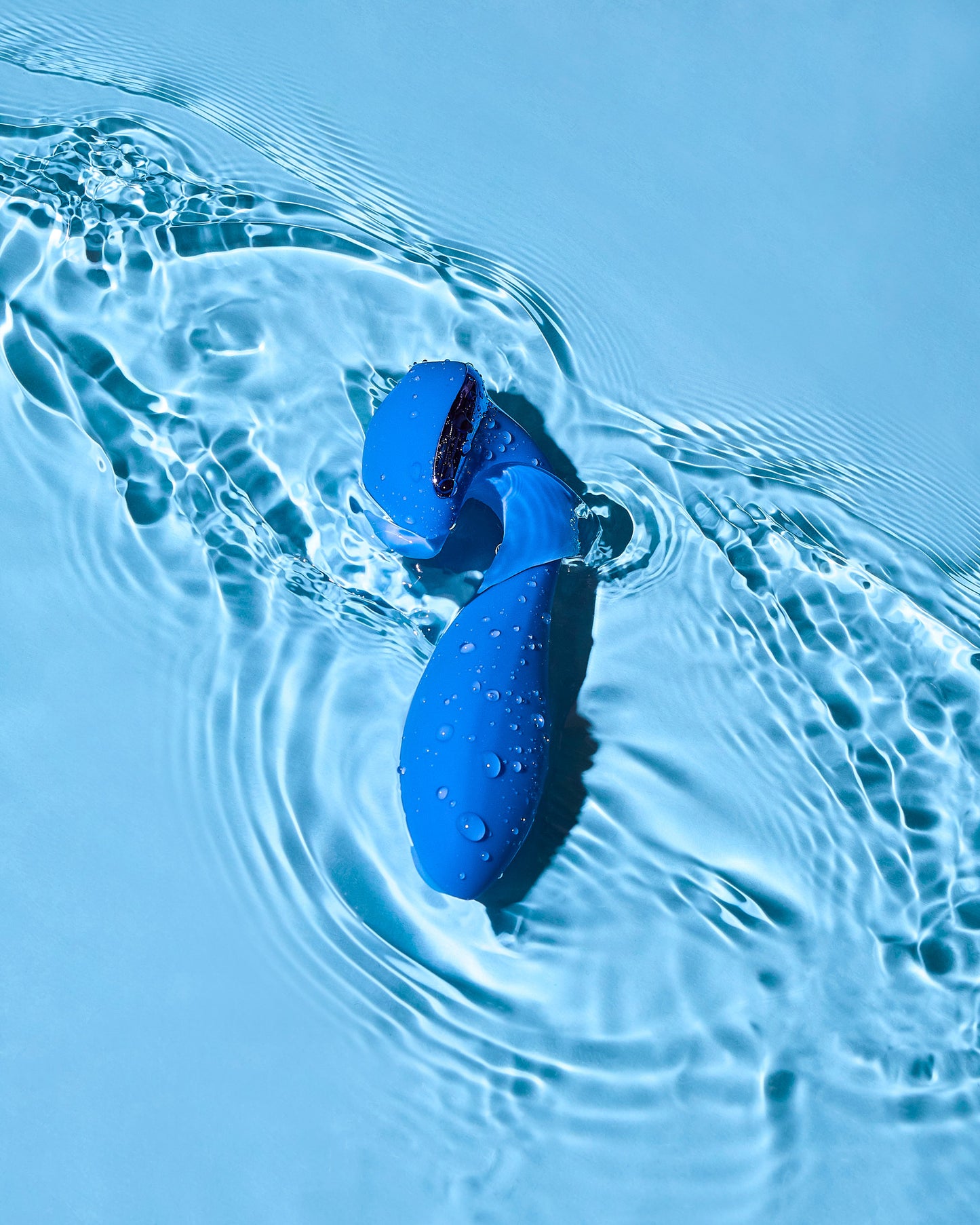 Blue silicon vibrator floating on water with ripples