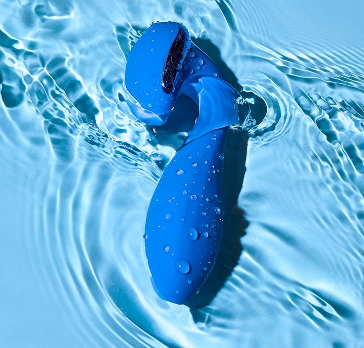 Blue silicone vibrator partially submerged in water with ripples around it