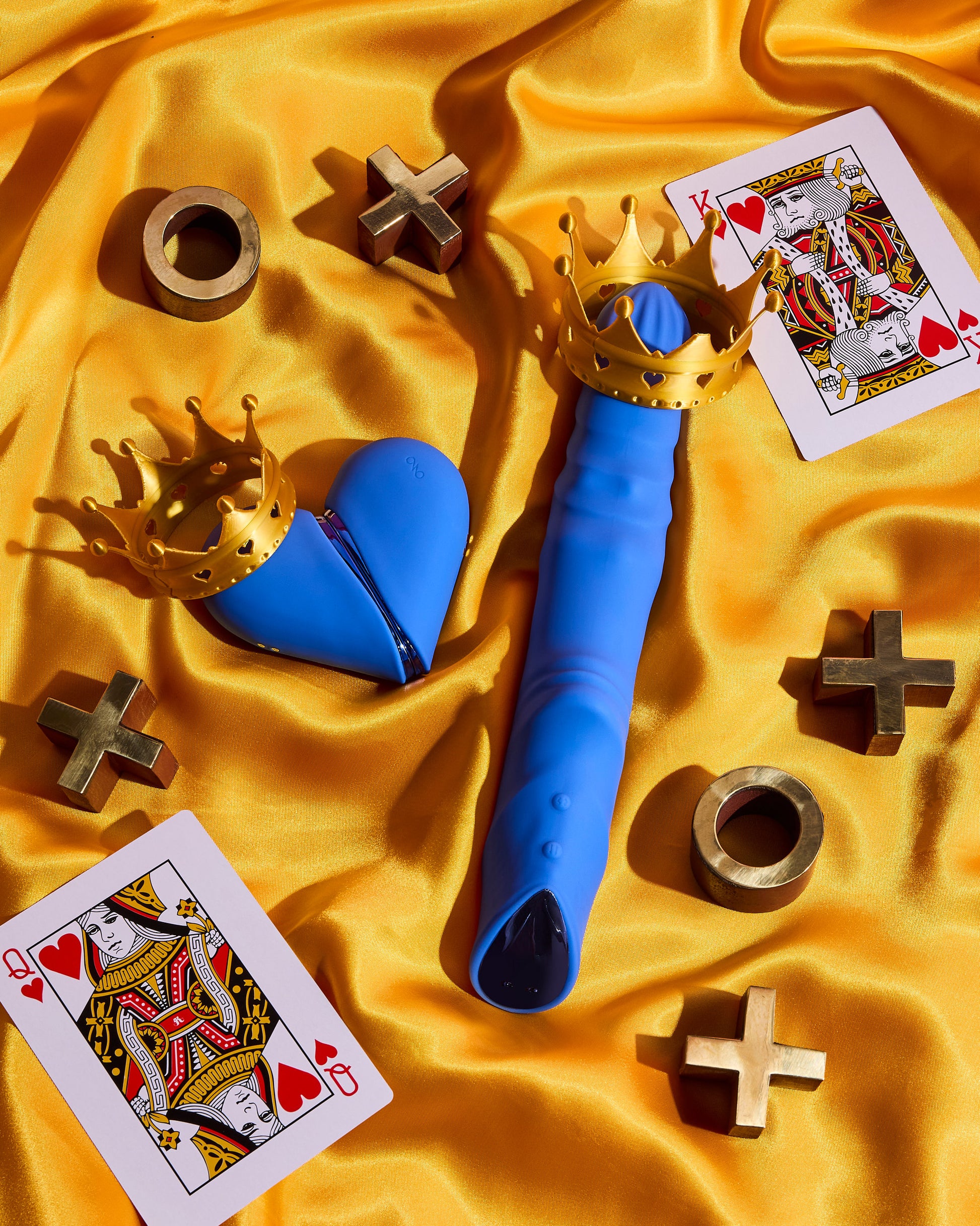 Blue toy with gold crown on a yellow fabric background with playing cards and gold symbols.
