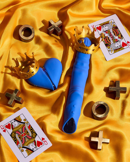 Blue toy with gold crown on a yellow fabric background with playing cards and gold symbols.
